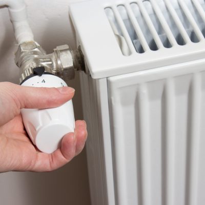 Closeup of a radiator thermostat with woman hand